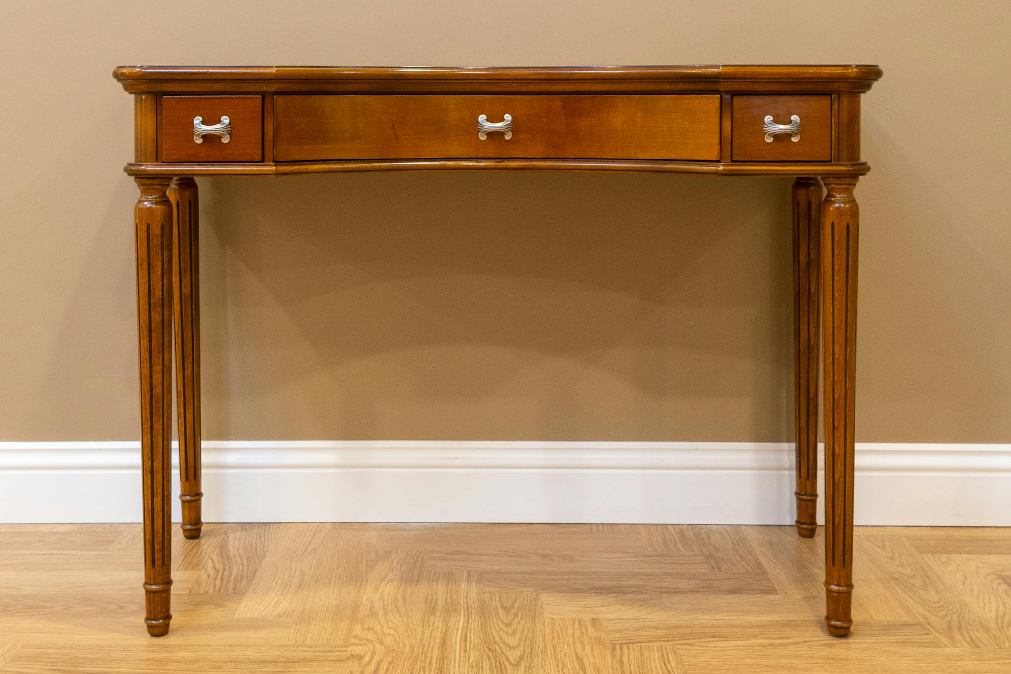 Elegant wooden console table featuring minimal design and three drawers with silver handles.
